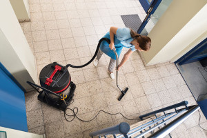 Femme de ménage passant l'aspirateur dans un hall d'immeuble